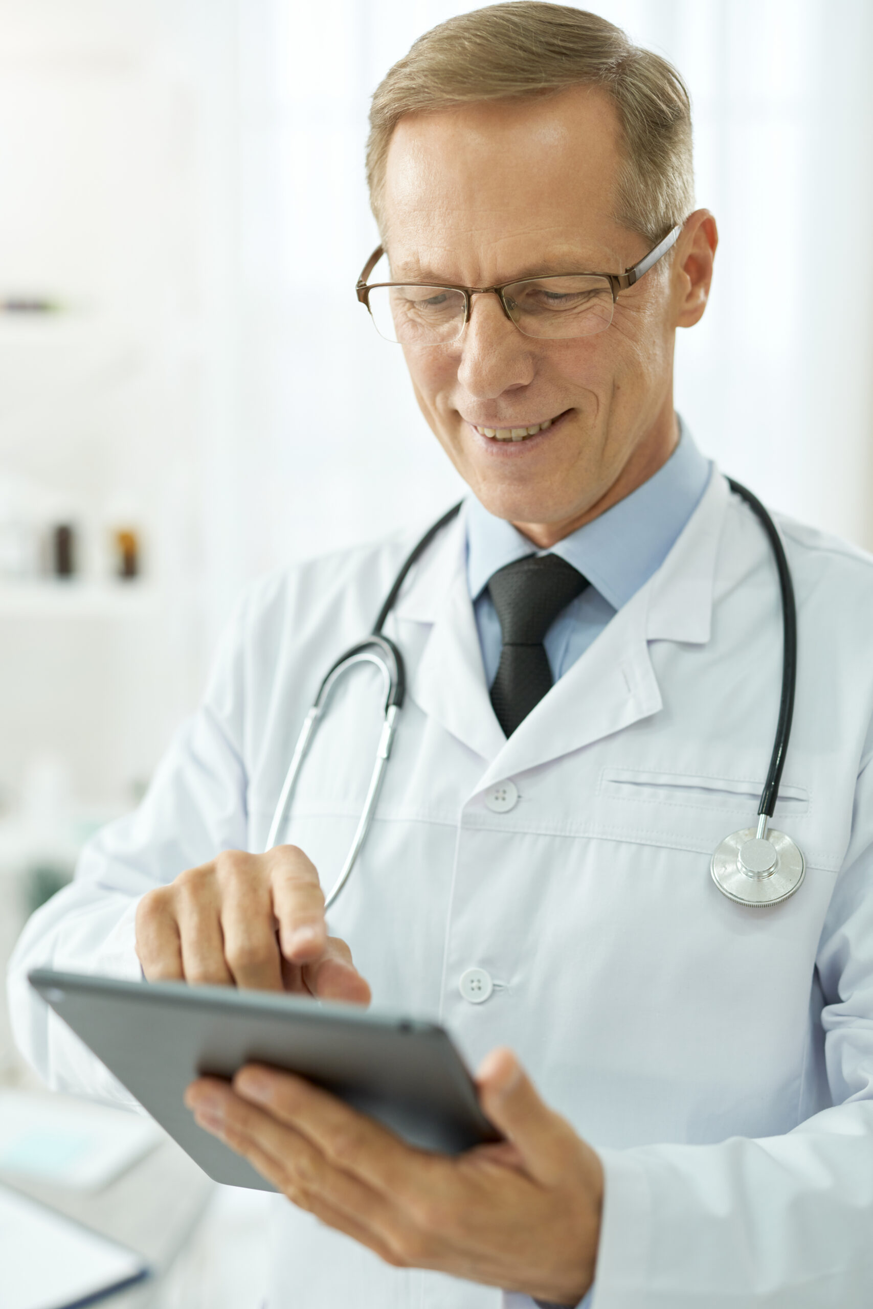 Cheerful male doctor using tablet computer in clinic